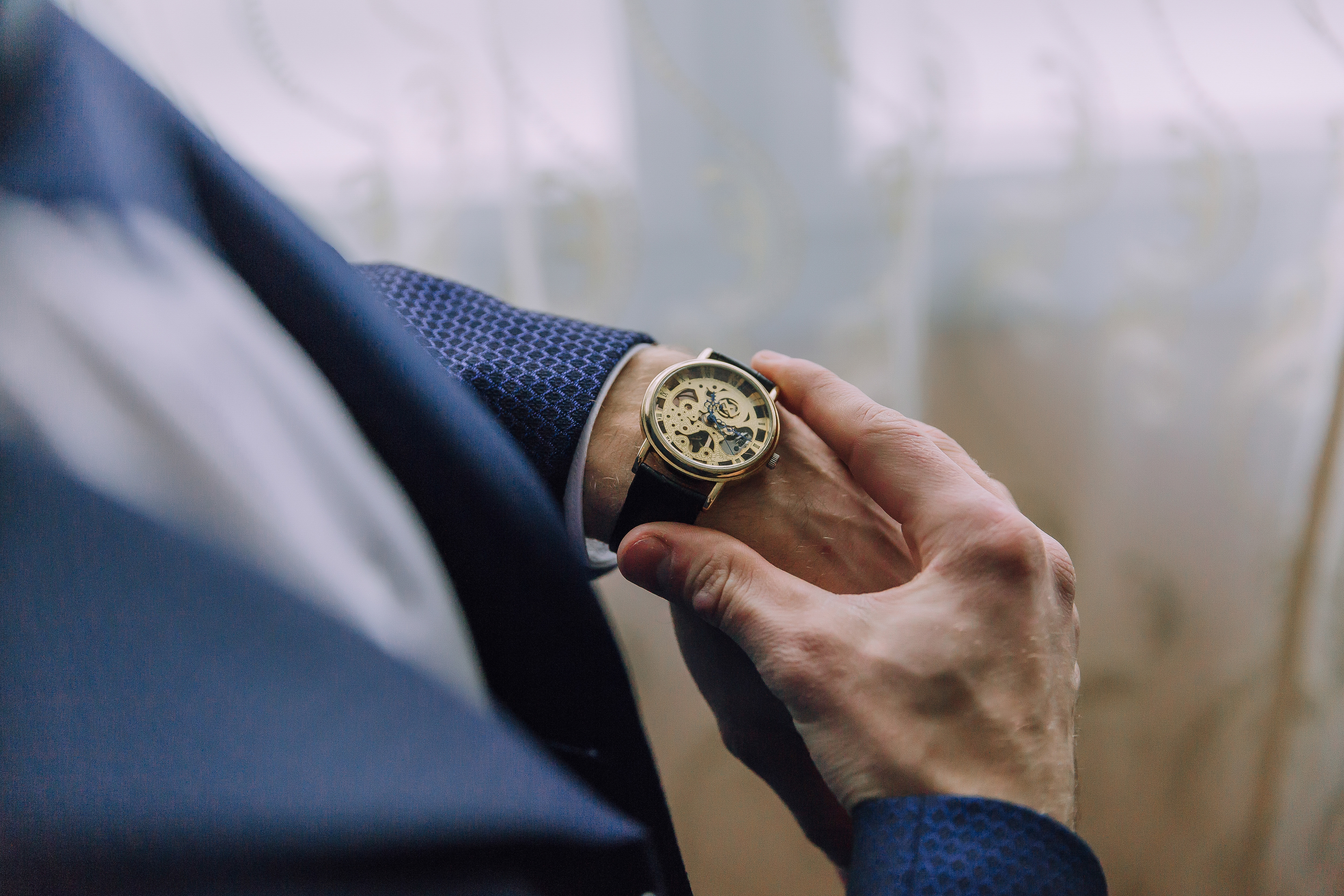 Hombre de negocios en traje observando su reloj mecánico dorado.