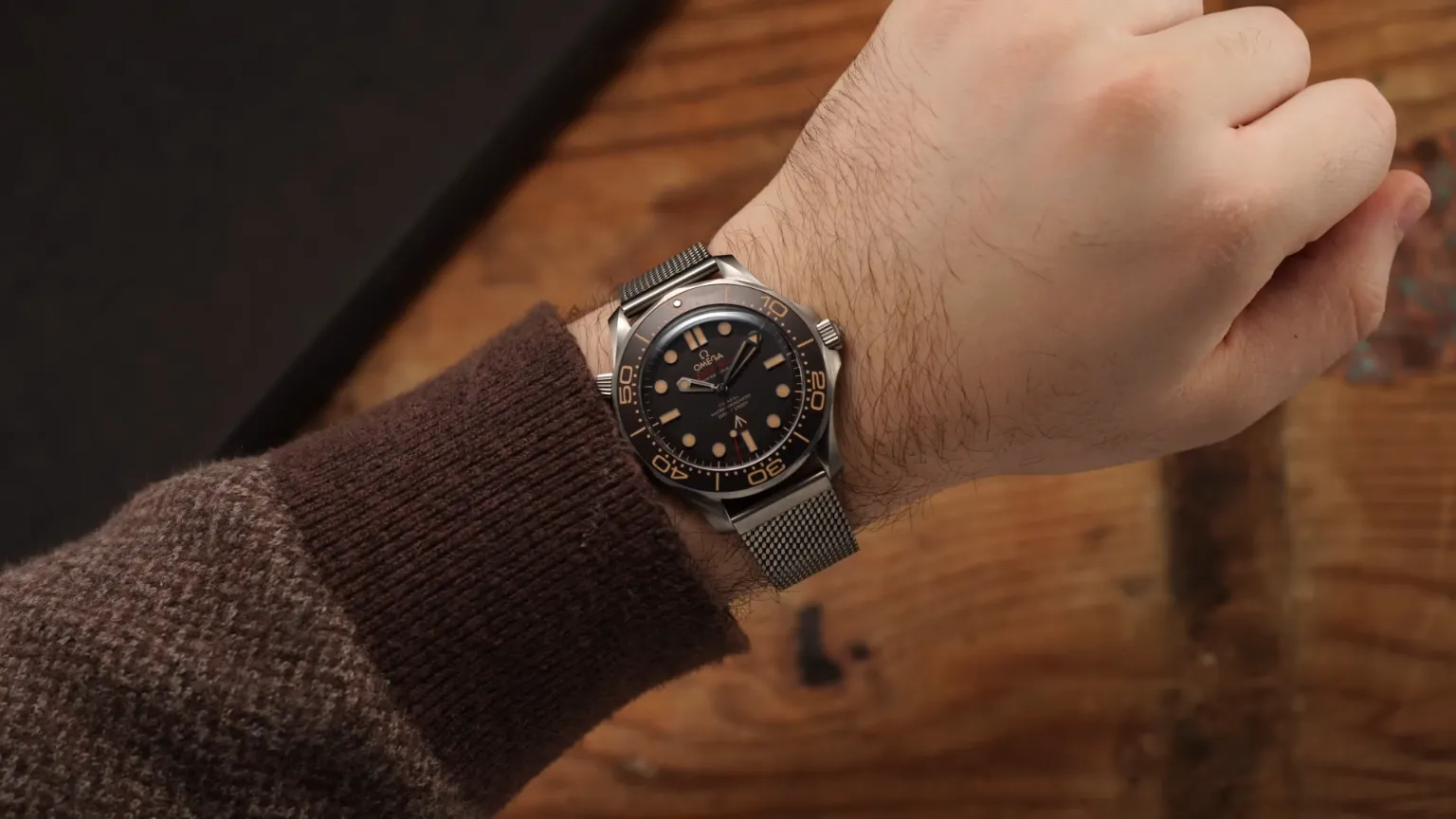 Reloj de pulsera Omega Seamaster con correa de malla metálica en muñeca masculina.
