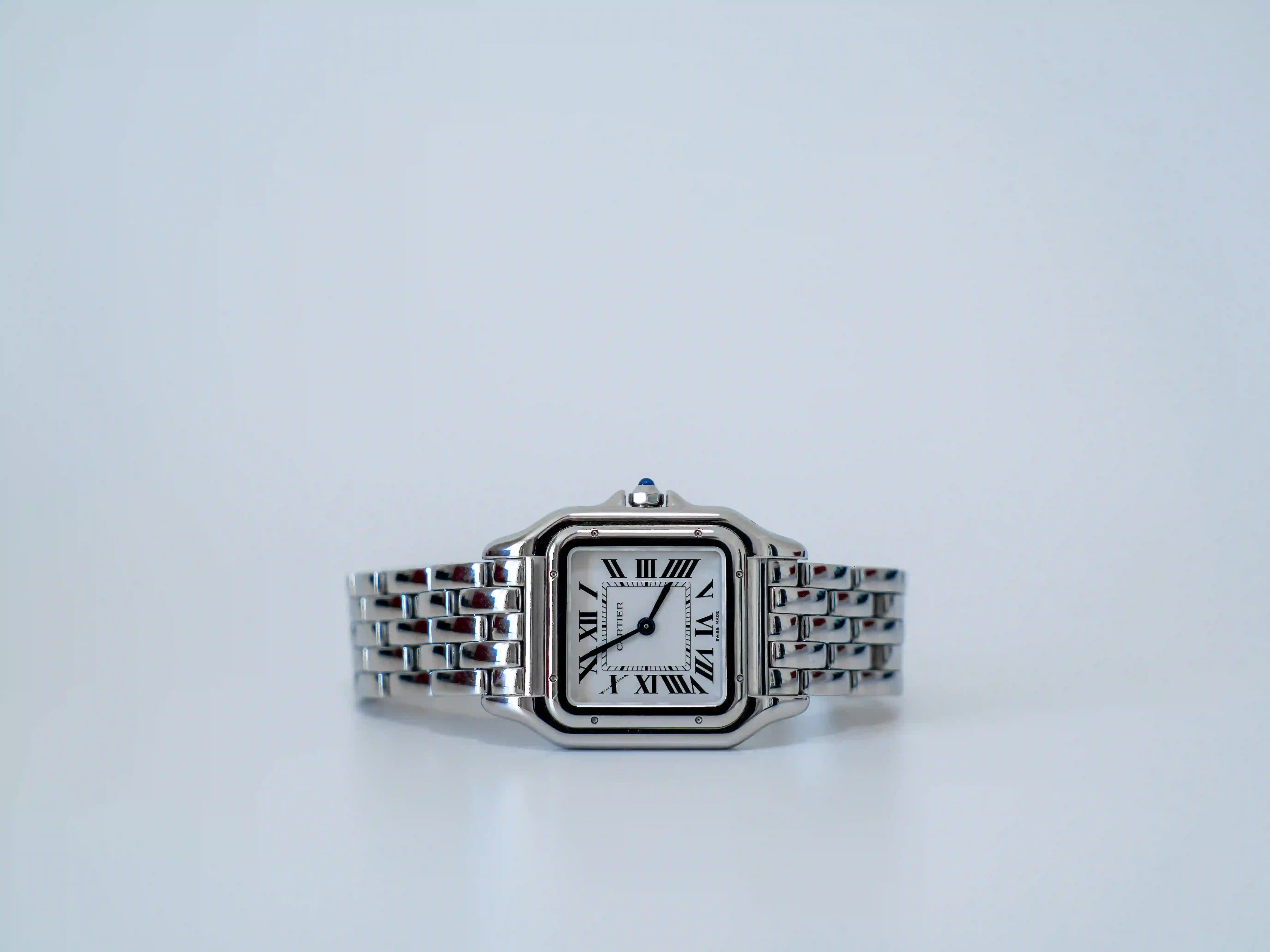 Reloj Cartier vintage de acero con esfera cuadrada y números romanos sobre fondo claro.