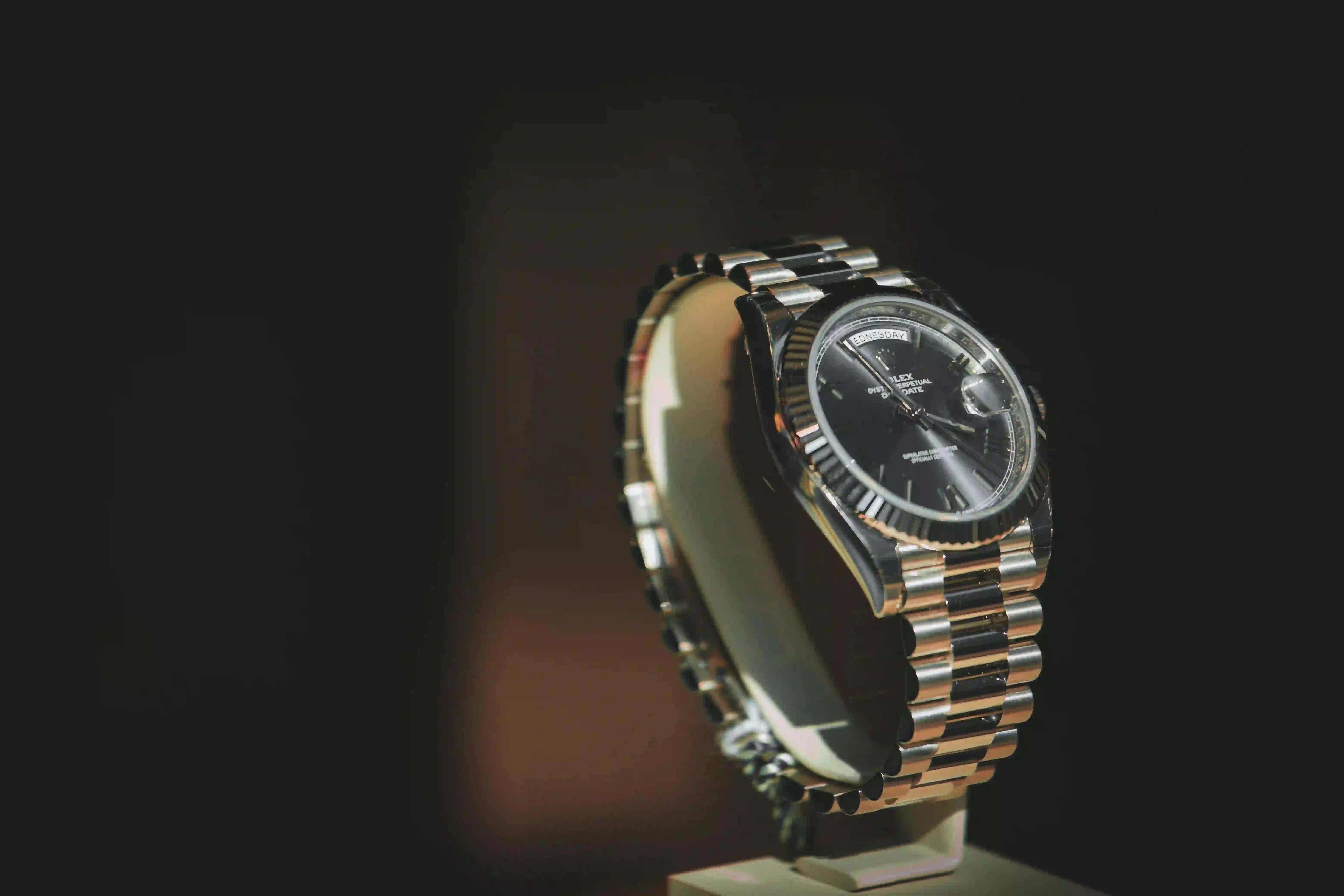 Reloj de lujo Rolex metálico bicolor sobre expositor con fondo oscuro y elegante.